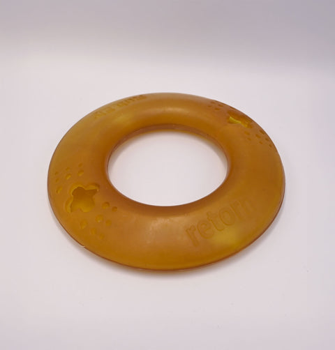 Round amber-colored Dog frisbee toy on a Grey background with visible branding.