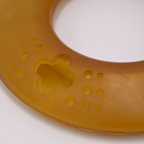 Round amber-colored Dog frisbee toy on a Grey background with visible branding.