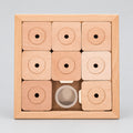 A wooden 9-piece sliding block puzzle set in a square light wood box, featuring nine square wooden pieces with circular cutouts and one round piece, shown on a white background.