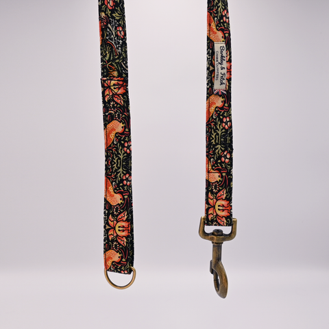 Floral patterned dog leash with brass hardware on a white background