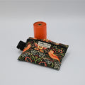 Poop Bag Holder and poop bag roll with a flower patterned design on a neutral background.