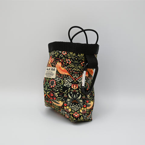 Floral-patterned pet treat pouch with a black base on a light neutral background.