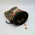 Floral-patterned pet treat pouch with a black base on a light neutral background.