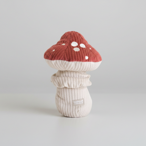 Mushroom-shaped plush toy with red cap and white spots on a white background