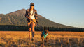 Woman walking a dog in a field with mountains in the background