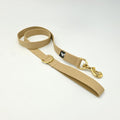 Beige dog leash with gold clip on a white background