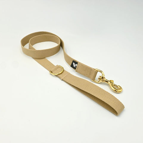 Beige dog leash with gold clip on a white background