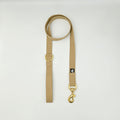 Beige dog lead with gold hardware on a light gray background