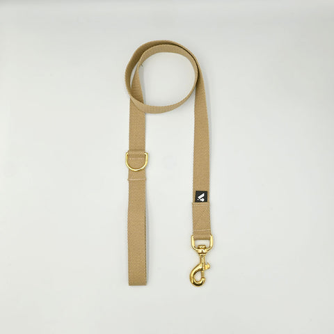 Beige dog lead with gold hardware on a light gray background
