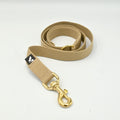 Beige dog lead with gold clasp on a white background