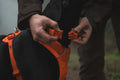 Person adjusting a Ruffwear Front Range Collar, Blaze Orange on a black dog outdoors.