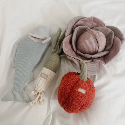 Three soft toys including a flower, a fish, and an apple on a white background