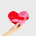 Heart-shaped plush toys with cartoon faces held by a hand on a white background