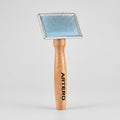 Grooming brush with wooden handle and metal bristle head on a white background, branded 'Artero'.