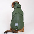 Dog wearing a green raincoat with a visible brand label on a white background