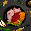 Assorted raw fish and seafood on a dark surface with garnishes