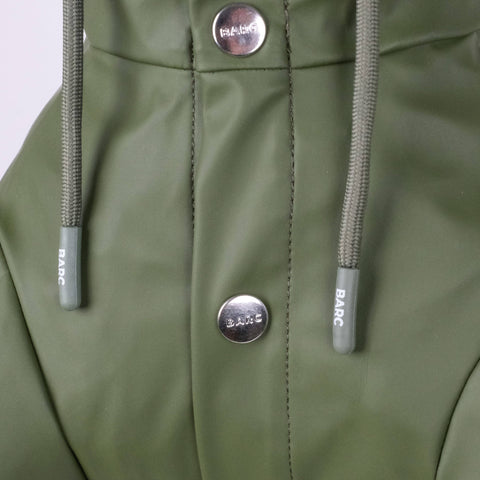 Close-up of a green jacket with buttons and drawstrings on a light gray background