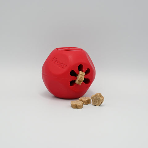 Red dog toy with a central hole and three treats on a light neutral background.