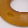 Round amber-colored Dog frisbee toy on a Grey background with visible branding.