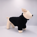 Stuffed animal wearing a black sweater on a light gray background