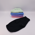 Stack of colorful knit sweaters with a black sweater in front on a light Grey background