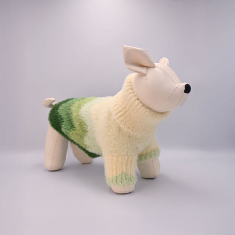 A dog manequin wearing a green and beige sweater on a grey background