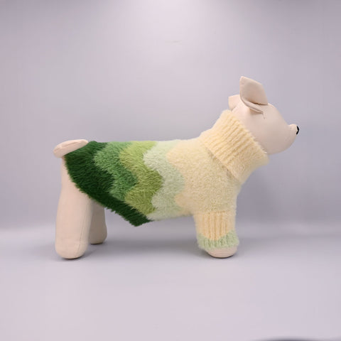 A dog manequin wearing a green and beige sweater on a grey background