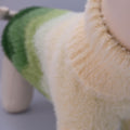 Close-up of a soft green and beige jumper on a neutral background