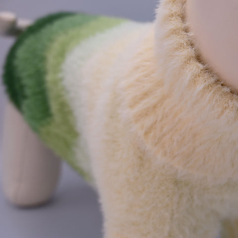 Close-up of a soft green and beige jumper on a neutral background
