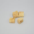 Four pieces of yellowish fish treats on a grey background