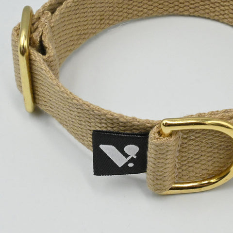 Beige dog collar with gold buckle and brand tag on a light gray background