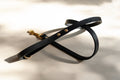 Black leather dog lead with gold clasp on a light background