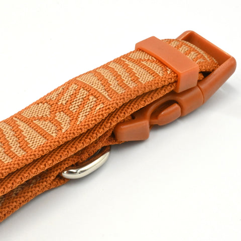 Close-up of an orange woven strap with a matching orange plastic buckle and a silver metal ring, shown on a white background.